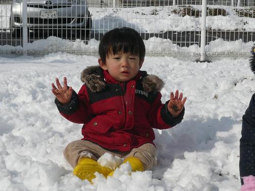 雪の上に座って遊ぶ子ども