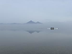 朝霧の中の猪苗代湖と磐梯山とボートを漕ぐ高校生