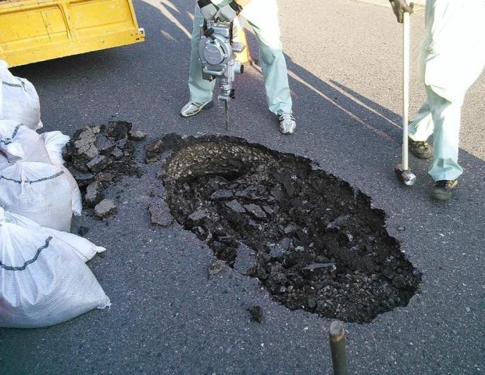 道路のアスファルト舗装が陥没している写真