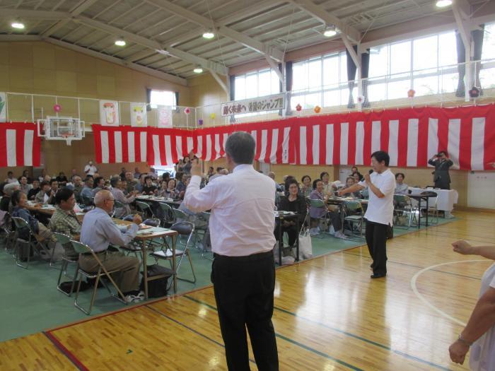 熱海町安子島地区敬老会で出席者とイベントスタッフが笑っている様子の写真