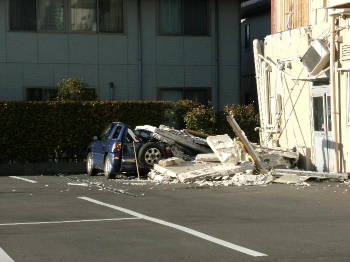 瓦礫の下敷きになった自動車の画像