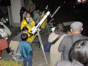 あ、見えた。望遠鏡をのぞく児童と指導するボランティアさん