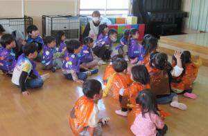 紫やオレンジのマントを身に着けハロウィンの話を聞いている児童たち