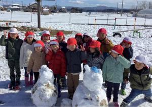 雪だるまと一緒に写真を撮る子ども達