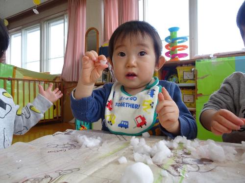 雪を嬉しそうにつかみ保育士に見せている子ども