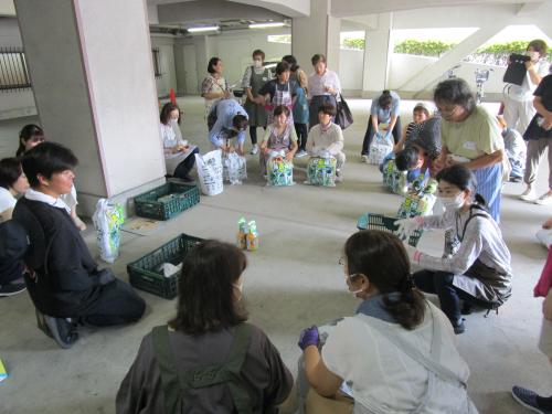 講師の説明を受けながら袋で野菜畑に種をまく受講者