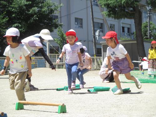 ひまわり組の子がエス棒や平均台やエス棒に向かって走っている