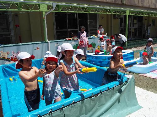 ひまわり組が友達と水鉄砲で遠くに向けて水を飛ばしている