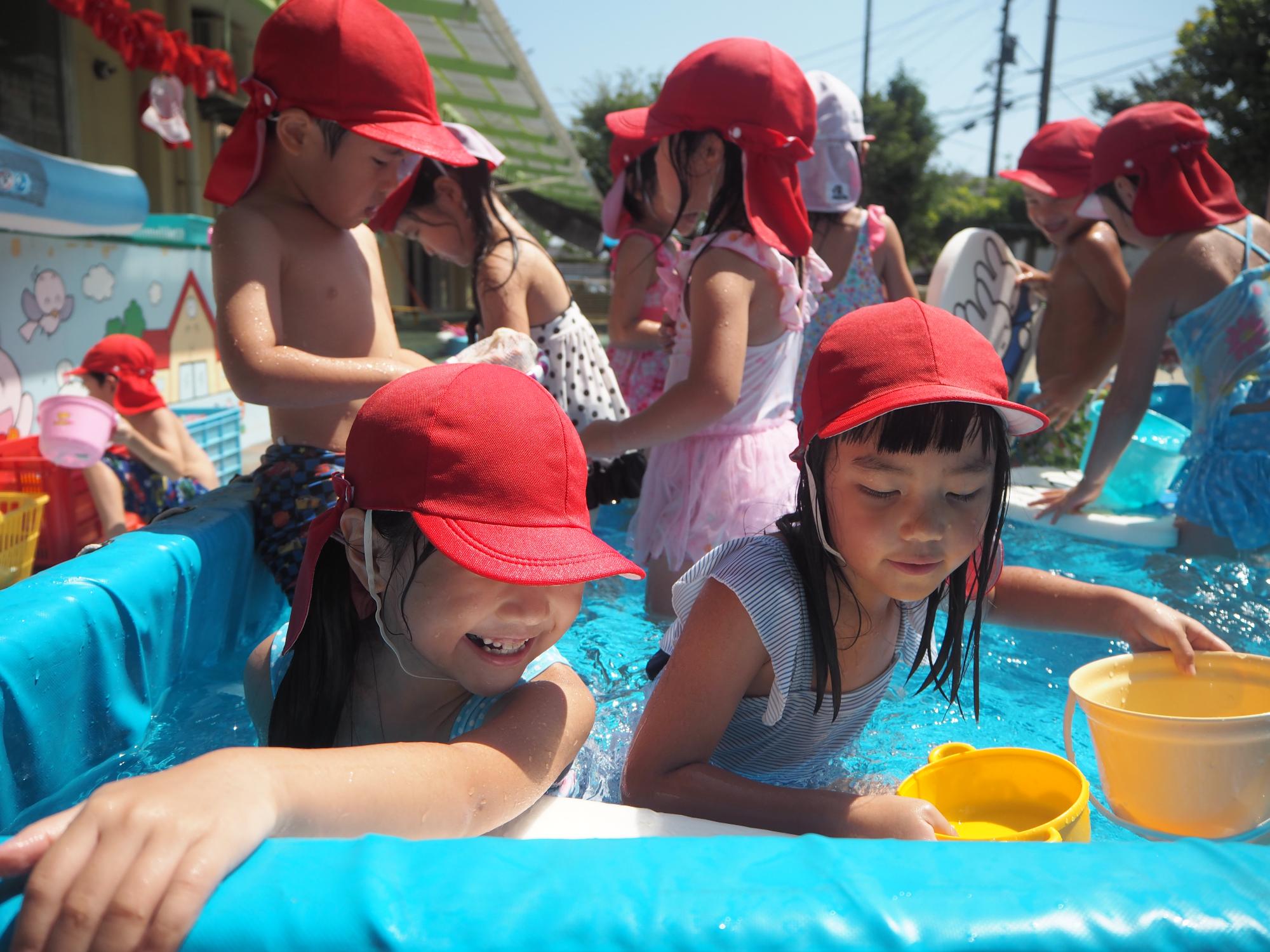 ひまわり組が大きいプールの中で友達とおしゃべりしながら遊んでいる
