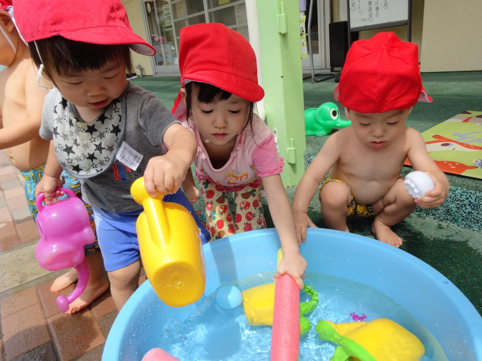 たんぽぽ組の児がタライで水遊びをしている