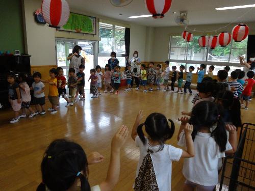 すみれ組とひまわり組で輪になって盆踊りを踊る