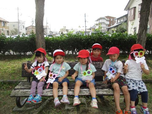 公園のベンチでトンボのメガネをつけて座るすみれ組の子ども達