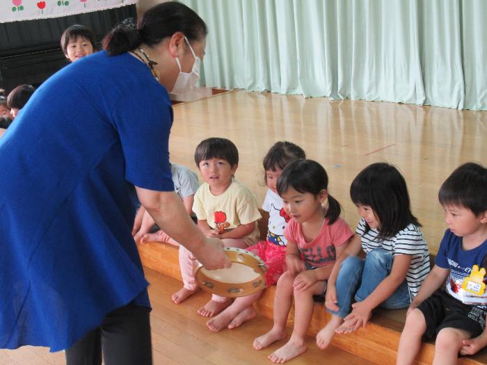 「おはよう」のあいさつにあわせてタンブリンをたたいている女の子