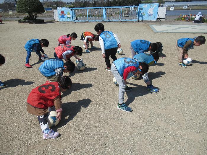 股の下でボールを転がす子供たち