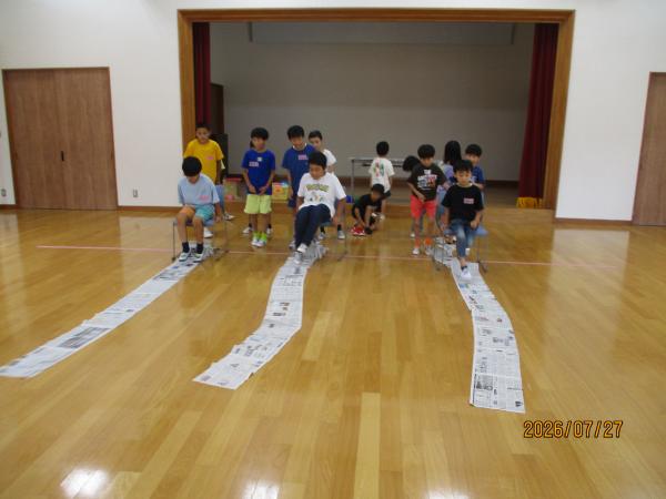 足で新聞紙をよせている