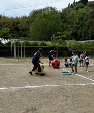 大きなサッカーボールを転がす競技を職員と一緒にしている児童