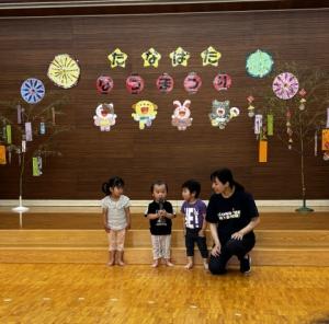 小さい女児がマイクを持って夏祭りのはじめの言葉を言っている