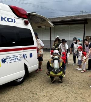 救急車の中を見ている保育所の児童と保育士