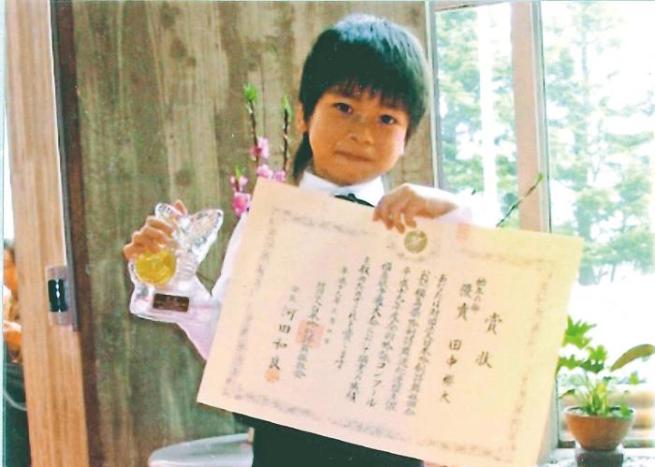 田中さんが幼いころ大会で優勝し賞状を手にする画像