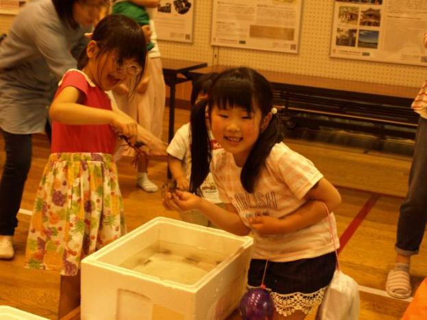 ほたる祭りで昆虫などに触れて喜ぶ子どもたちの写真