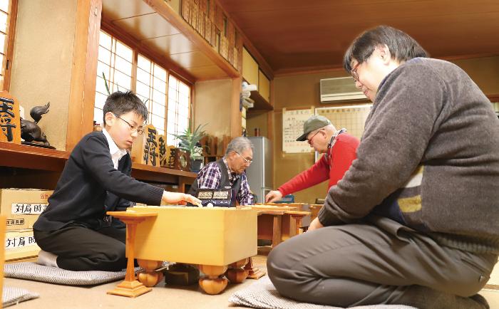 将棋センターで大人と対戦する古川雅也さんの写真