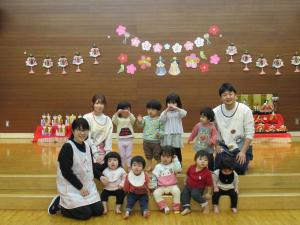 ひな人形を持って集合写真を撮るうめ組